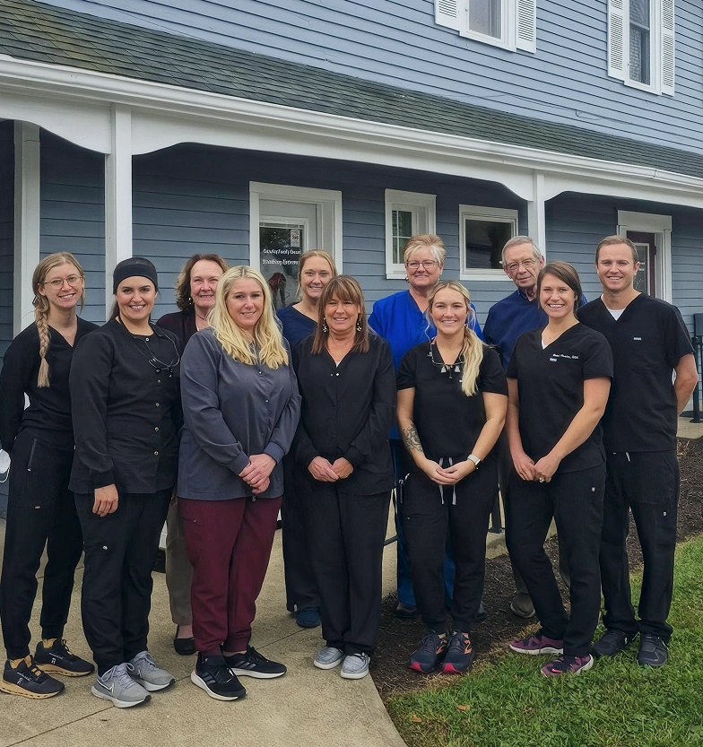 Dental care team members posing together outside their dental practice.